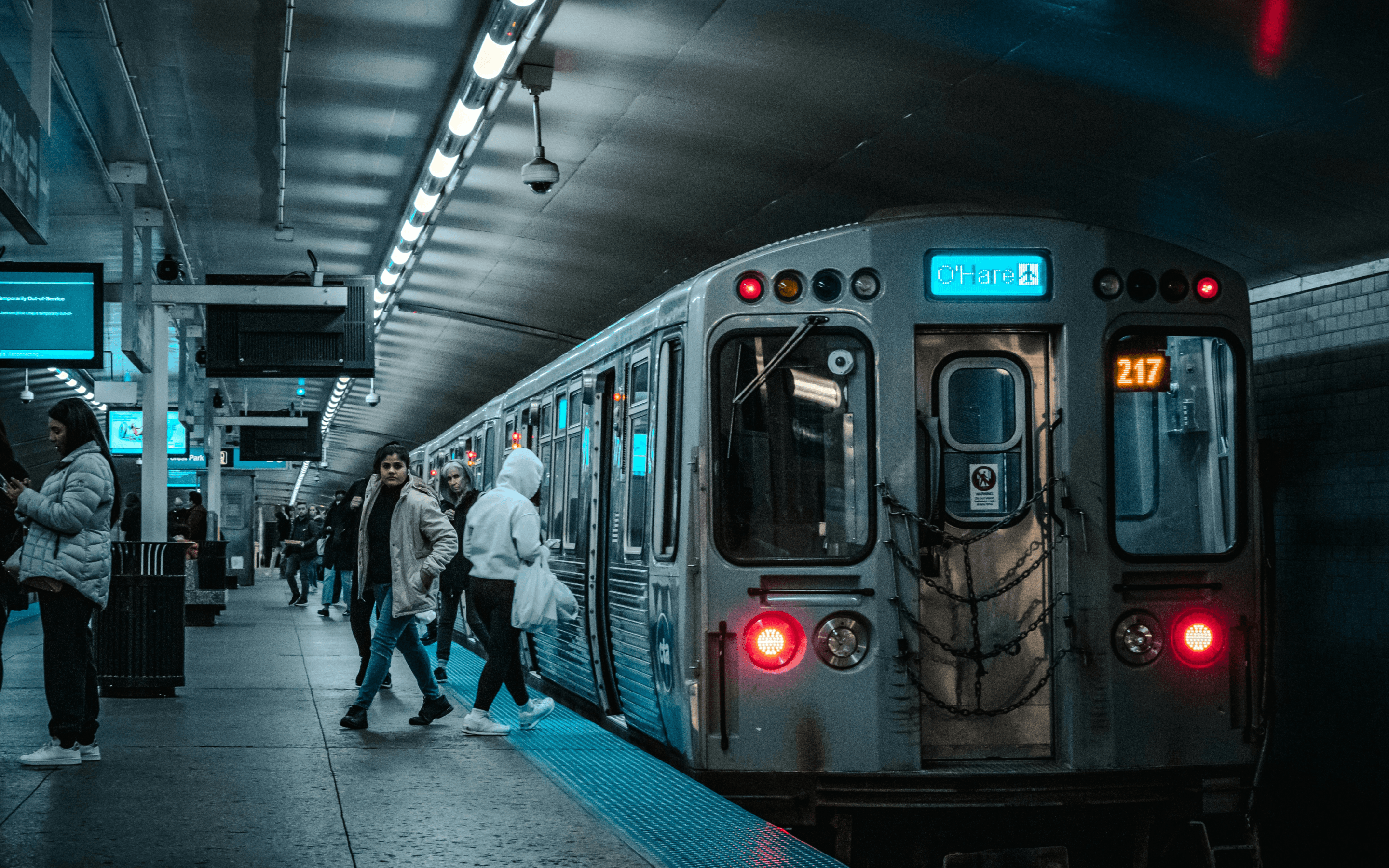 Chicago L train arriving at a busy CTA station platform during rush hour